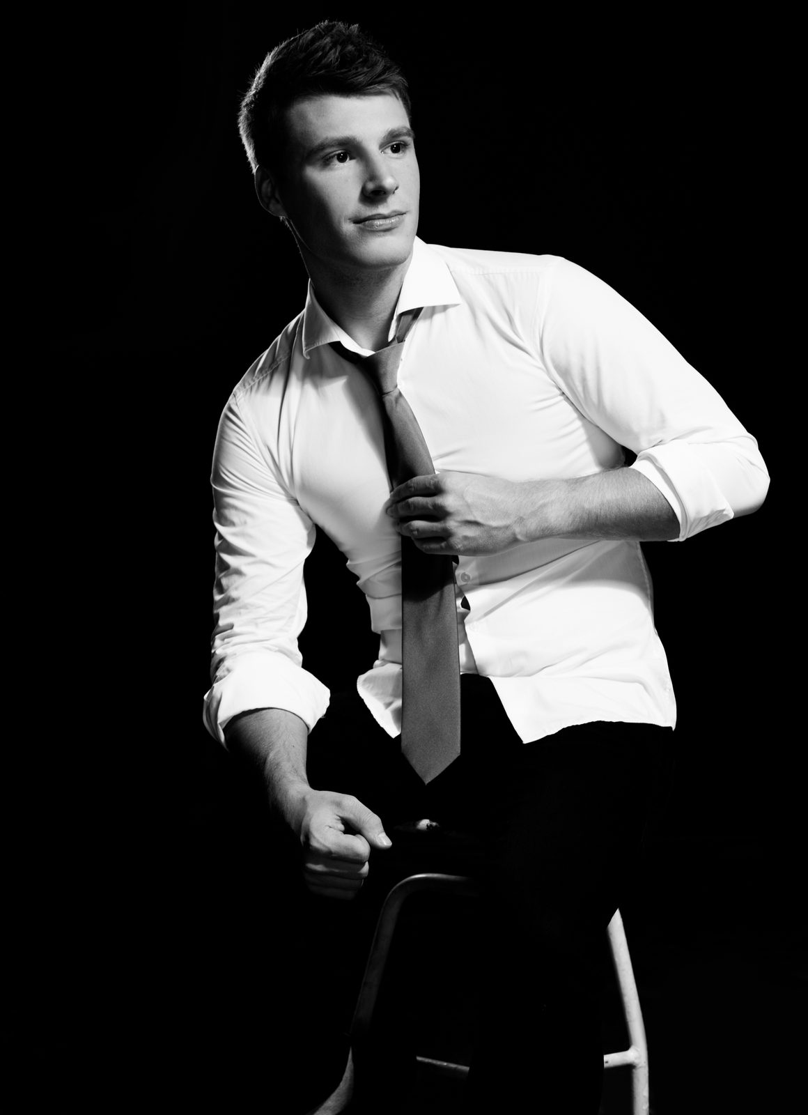 Young man in white shirt and tie, black and white studio portrait