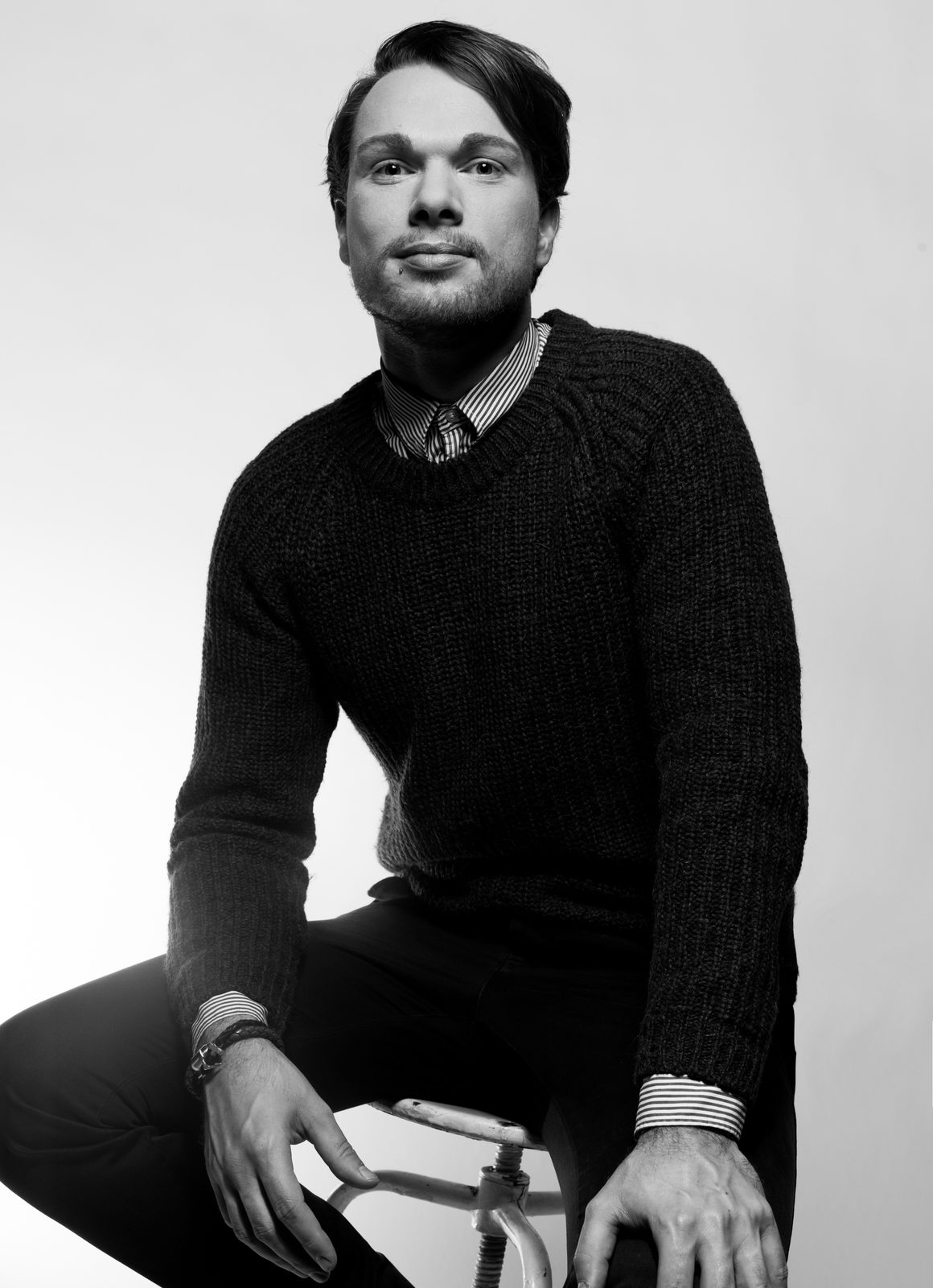 Black-and-white portrait of a seated man in a knit sweater — studio shoot in Hamburg