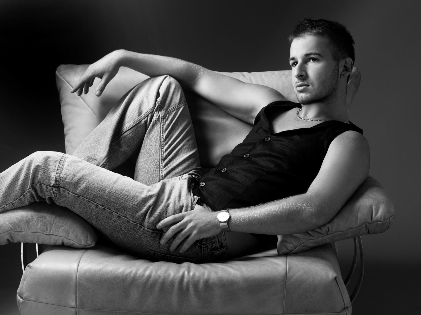 Mann in schwarz-weißem Porträt lässig in Ledersessel liegend – Fotostudio in Hamburg